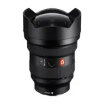 Sony FE 12-24mm F2.8 GM lens, angled front view showing the bulbous front element inside the fixed petal hood, AF/MF switch, focus hold button and zoom scale